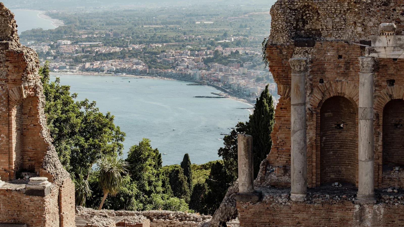 Ancient Greek Theatre of Taormina, Sicily, with its dramatic ruins overlooking the sparkling Ionian Sea and the town below. A highlight stop on our Road to Rome tour combining ancient history with the beauty of Sicily.