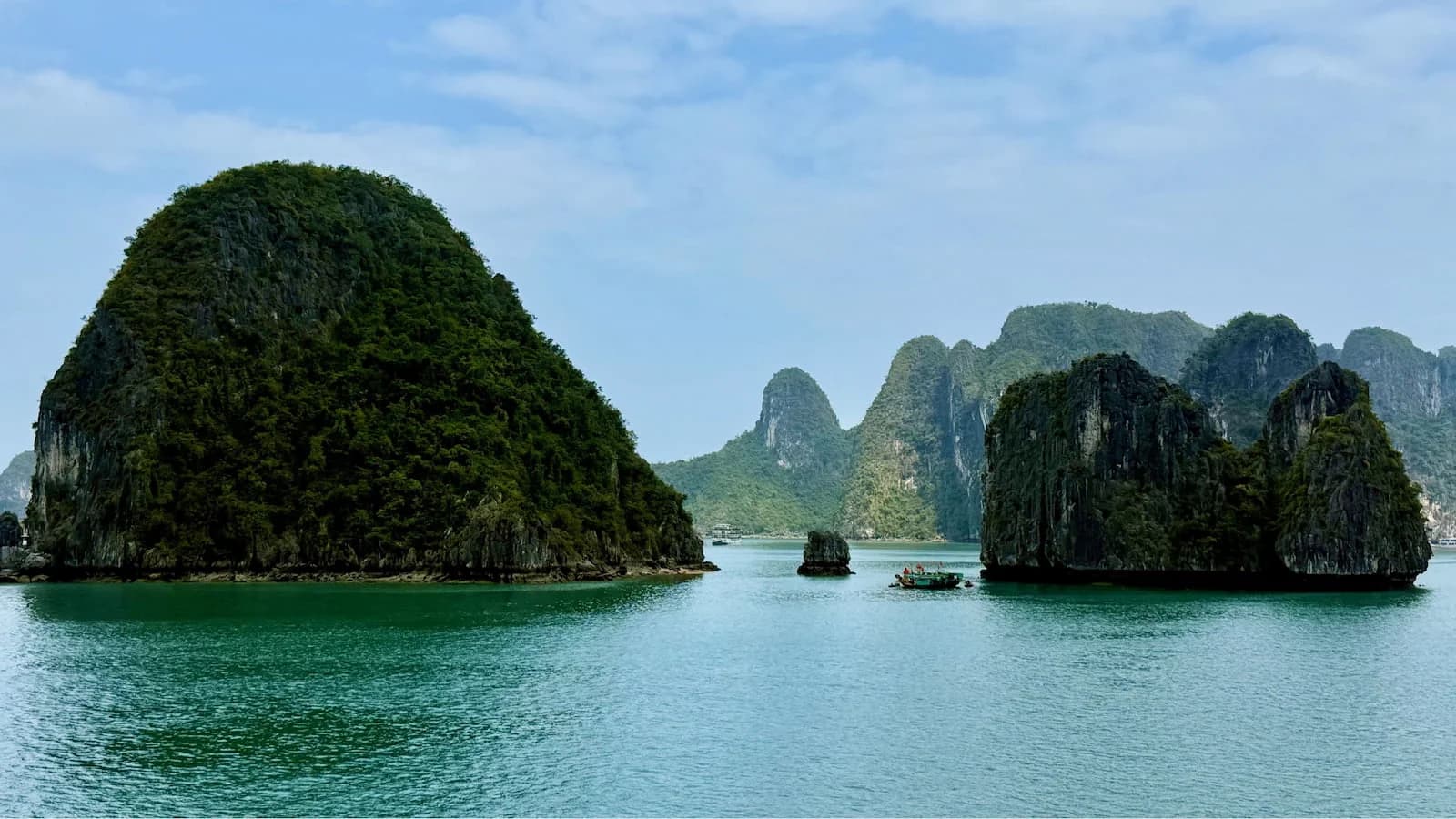 Iconic limestone karsts rising from the emerald waters of Halong Bay, a UNESCO World Heritage site. One of the most breathtaking natural wonders visited on our Essential Vietnam tour.