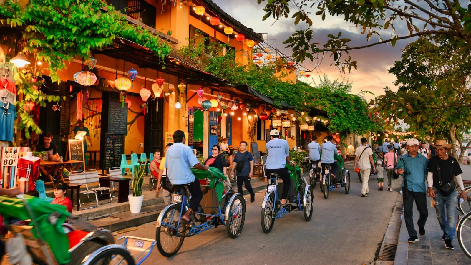 Lively evening street scene in Hoi An Ancient Town with colorful lanterns, traditional architecture, and cyclo rickshaws, a highlight of Essential History Expeditions’ Vietnam history and culture tour.