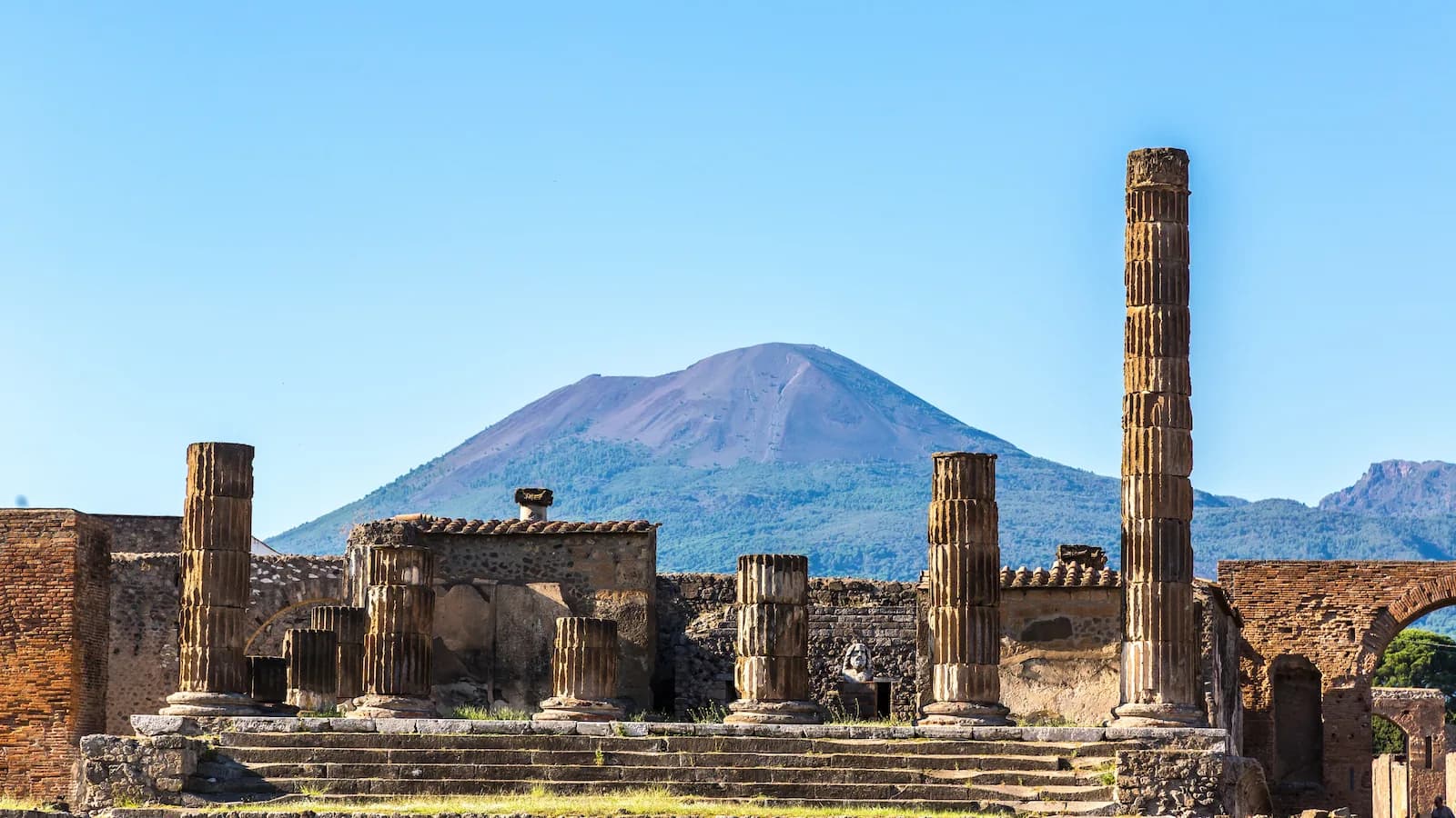 Ruins of Ancient Pompeii stand in the foreground with Mount Vesuvius looming behind it. Enjoy time exploring this incredible location on the Sicily and Italy Campaign expedition.