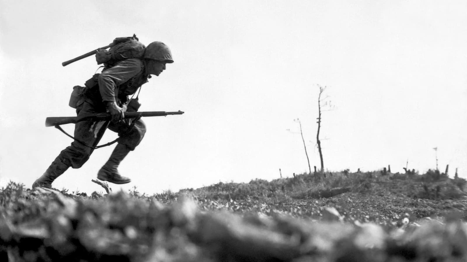 U.S. Marine dashing forward under fire during the brutal Battle of Okinawa, 1945. One of the most iconic images of the Pacific War, capturing the intensity of the final major campaign before the planned invasion of Japan.