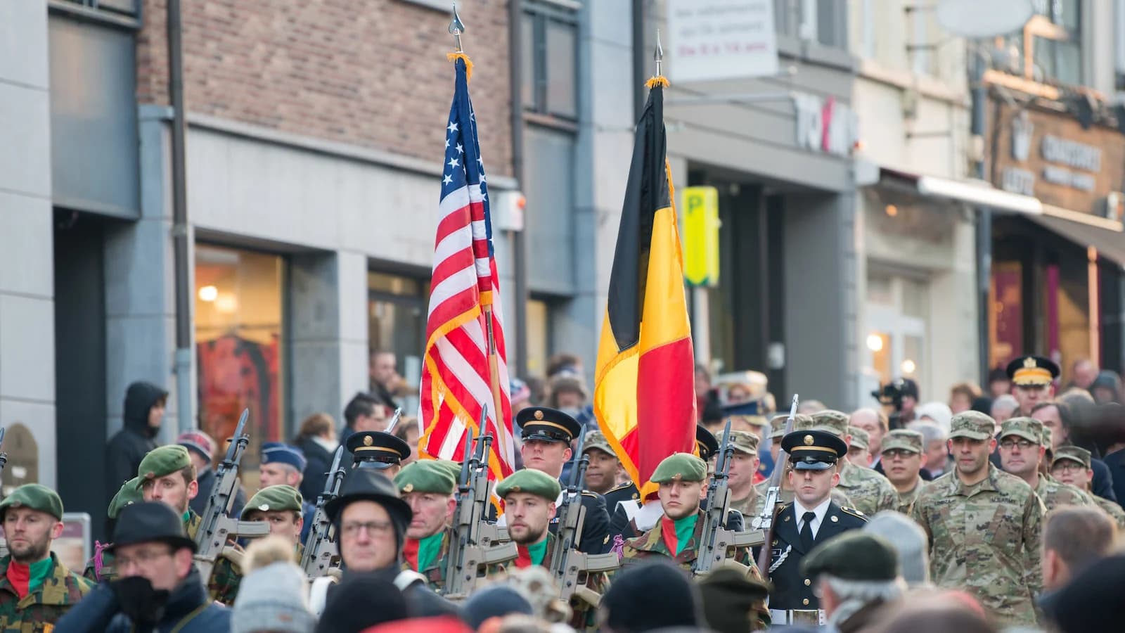 U.S. and Belgian soldiers marching with flags during a Battle of the Bulge anniversary parade in Bastogne. Special commemoration events are included on our 85th Anniversary tour, December 2029.