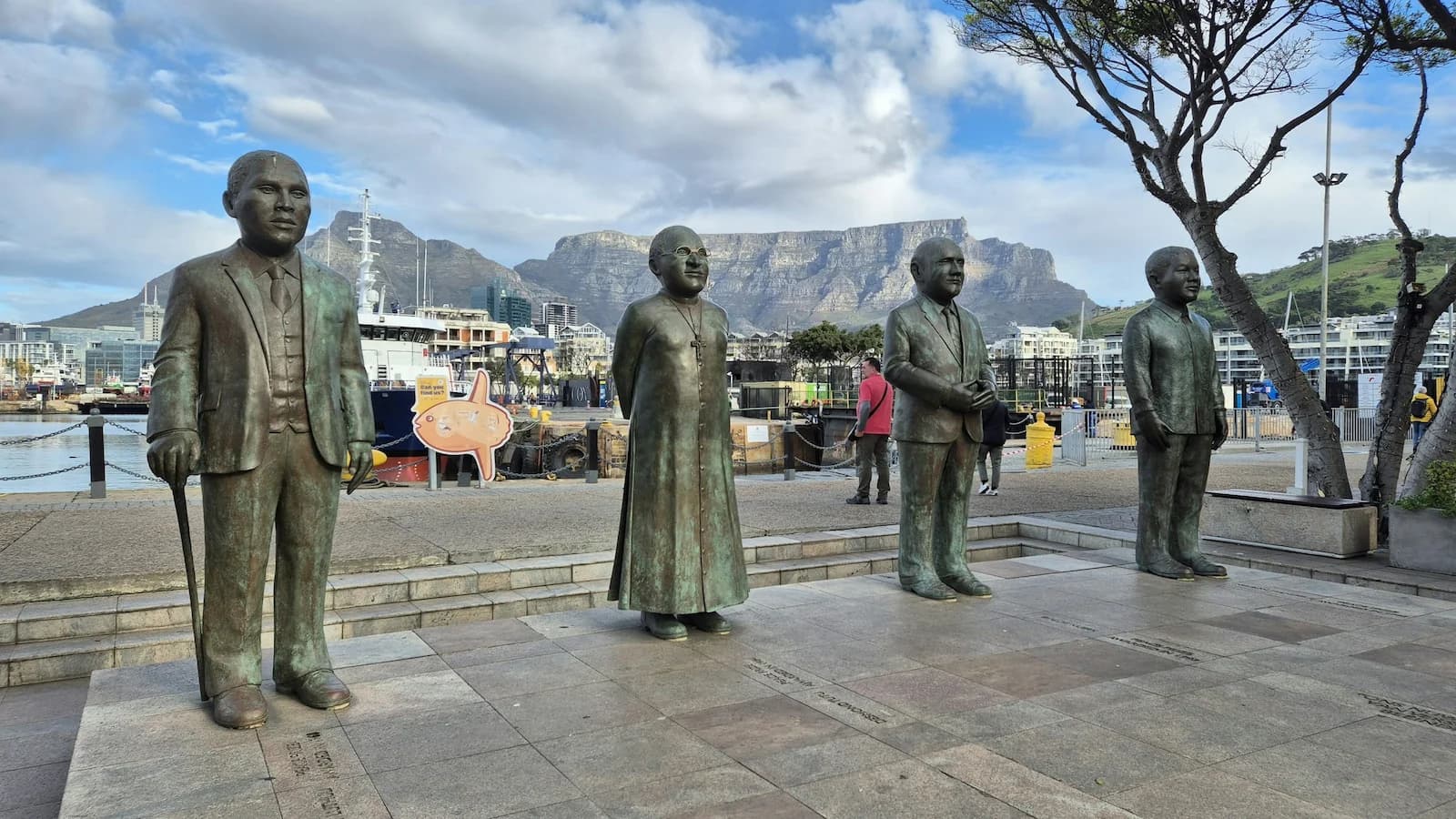 Bronze statues of Nelson Mandela, Desmond Tutu and other icons at the Victoria & Alfred Waterfront in Cape Town, with Table Mountain in the background.