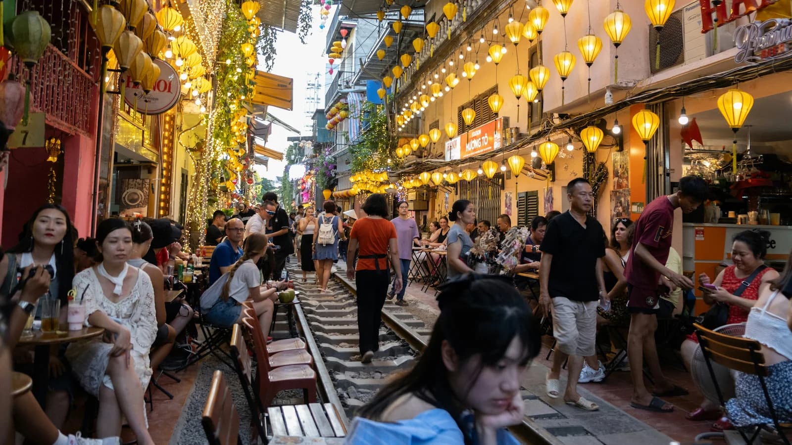 Vibrant evening scene on Hanoi’s famous Train Street, where diners and visitors sit and walk along the narrow railway tracks beneath glowing yellow lanterns. A lively and iconic spot in the Old Quarter visited during our Essential Vietnam: History & Culture expedition.
