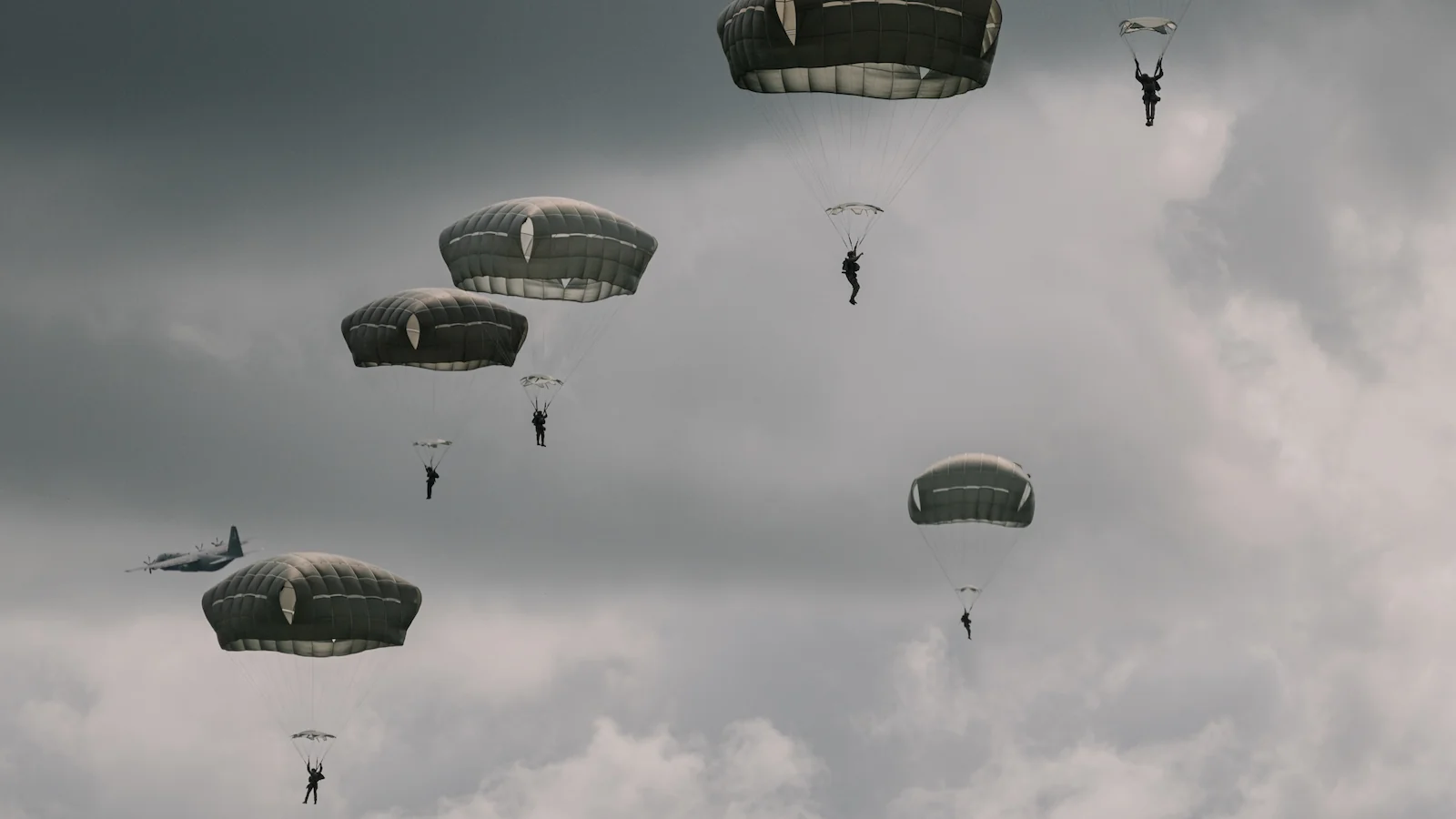 U.S. Army paratroopers descending under parachute during D-Day commemoration ceremonies over Normandy. A powerful modern tribute to the airborne assault that began the liberation of Europe on June 6, 1944.